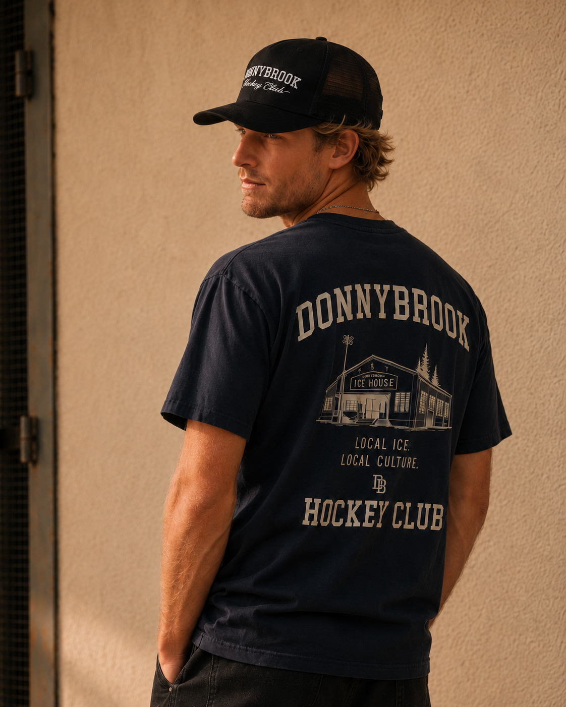 Navy Donnybrook Local Ice House back-graphic tee and black club trucker, stucco wall